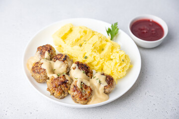 Swedish noisettes (fricandel) with mashed potatoes, Brune Sos creamy sauce and lingonberry (cranberry) sauce. Traditional meatballs with garnish. Selective focus, close-up.