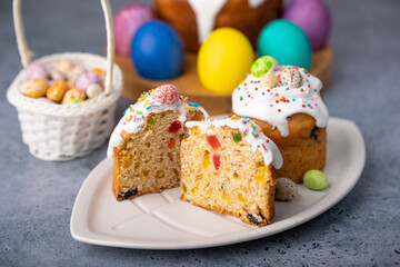 Two small Easter kulichs with candied fruits in white glaze with colorful sprinkles in the cut....