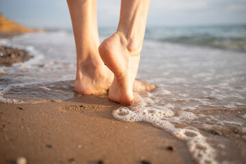  a pair of bare feet belonging to a woman resting on the sandy shore, poised at the edge of the...
