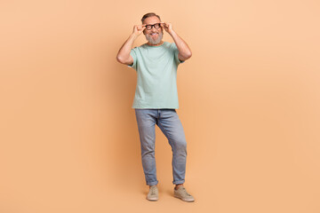 Full length portrait of cheerful aged person hands touch eyewear empty space isolated on beige...