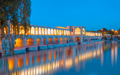 People resting in the ancient Khaju Bridge at twilight blue hour - Isfahan, Iran