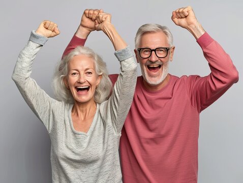 happy elderly couple with hands in the air photostock
