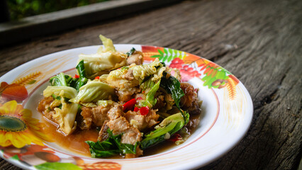 Stir fried kale with crispy pork in oyster sauce on white plate