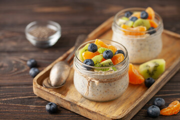Healthy diet breakfast. Overnight oatmeal with chia seeds and fruits in a glass jar on a wooden background.