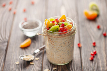 Healthy diet breakfast. Overnight oatmeal with chia seeds and fruits in a glass jar on a wooden background.