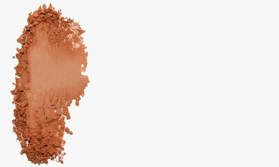 Close-up smear of orange eyeshadow, blush and powder on a light background