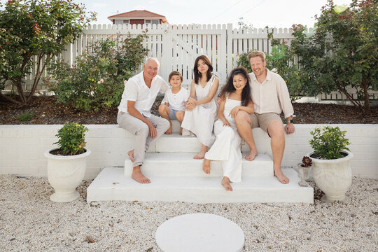 Family of five sitting on backyard steps