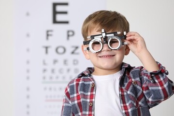 Little boy with trial frame against vision test chart