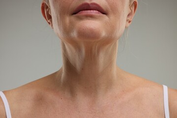 Mature woman with healthy skin on grey background, closeup