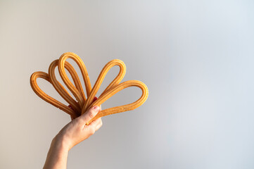hand holding several churros, full of fat and oil, typical Spanish