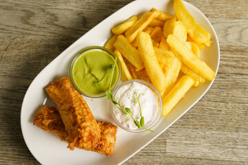 Fish and chips with tartare sauce on wooden table