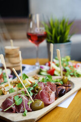Selection of prosciutto, local cheese, chorizo sausage and vegetables on a wooden plate