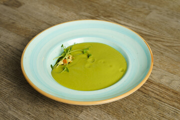 Green peas cream soup with parenica cheese on a wooden table