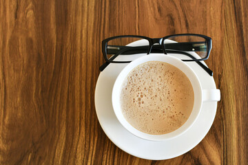 Lentes y un café con leche, espacio para texto al lado izquierdo.
