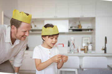 Father and son wearing yellow crowns reading Christmas cracker joke