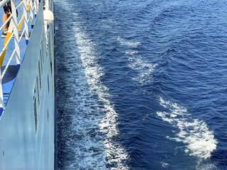 A side view of a large ferryboat sailing across the clear blue sea, illustrating marine travel and transportation