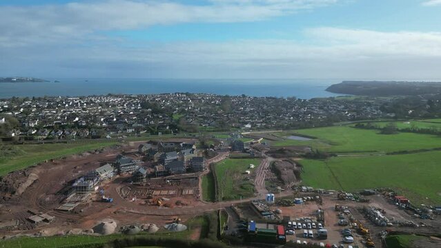 Paignton, South Devon, England: DRONE VIEWS: The drone circles a new build housing development under construction on green belt land at White Rock. Paignton is a popular UK holiday resort (Clip 1).