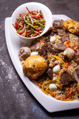 Traditional Uzbek Plov Dish with Mutton, Carrots, and Rice on White Plate.