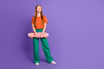 Photo of cheerful adorable girl wear trendy clothes hold skateboard enjoy summer season empty space ad isolated on purple color background