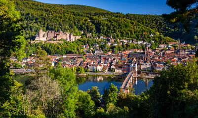 Panorama of the historic old town of Heidelberg am Neckar in Baden-Württemberg, Germany on a beautiful summer day. Castle, bridge, churches and other listed buildings seen from the Philosophenweg. - obrazy, fototapety, plakaty