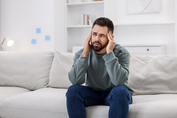 Man suffering from headache on sofa at home