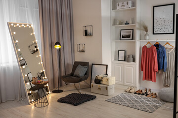 Makeup room. Stylish mirror with light bulbs, clothes and shoes indoors