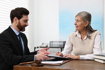 Senior woman signing document in lawyer's office