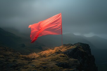 a red flag sticking out of the side of a mountain on a foggy day with mountains in the background.