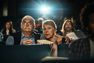 Senior couple watching a movie in the theater with popcorn