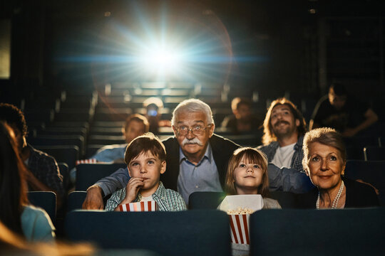Grandparents with grandchildren in the movie theater watching a film