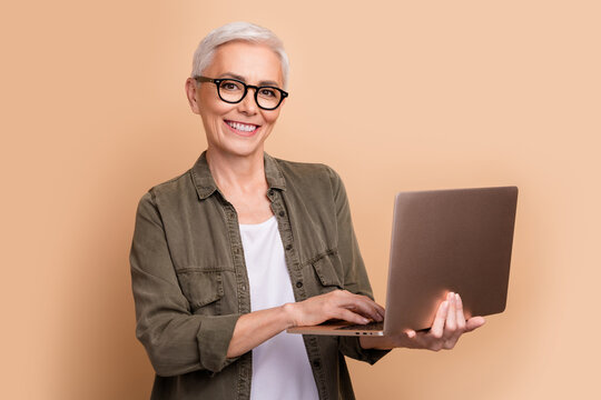 Photo of it specialist mature age woman strong middle level python developer using laptop linux isolated on beige color background