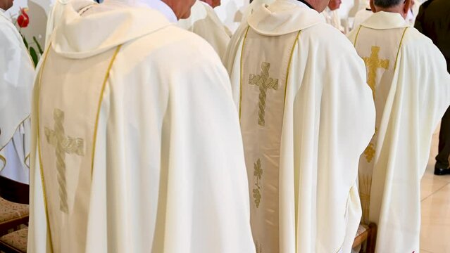 Catholic priests in liturgical vestments praying in church. Christian priests praying in Cathedral. Cross symbol. 