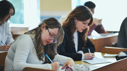 Girl students writing math formulas in a notebook.