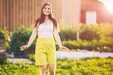 Portrait of woman in yellow Bermuda shorts, white female 26 years old posing for photographer near...