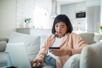 Young woman online shopping at home with credit card