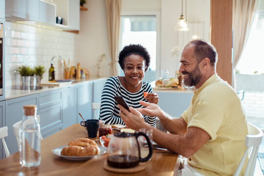 Diverse middle aged couple having breakfast together at home