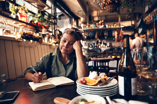 Senior waitress doing expenses at a restaurant table