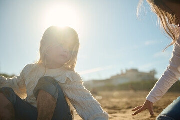 Two adorable little kids girls playing together on the beach, building sandy castle on warm sunny...
