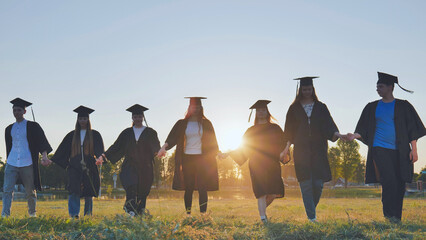 Graduate students walking through an evening meadow at sunset.