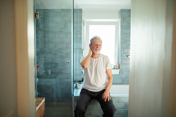 Fototapeta na wymiar Senior man in pain holding neck in bathroom at home