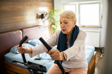 Senior woman working out on exercise bike at home