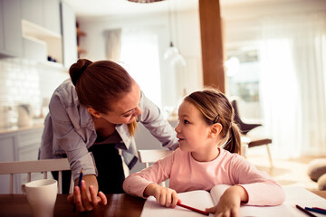 Mother helping little daughter with homework at home