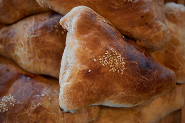 National Asian cuisine. Samsa, samosa, oven baked triangular pie sprinkled sesame seeds, with beef or chicken meat, close up top view. Traditional food of Uzbekistan Kazakhstan Tajikistan Kyrgyzstan