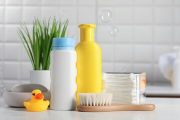 Baby cosmetic products, bath duck, brush and cotton swabs on white against soap bubbles