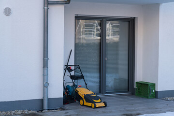 A yellow electric machine for cutting grass on the lawn near the door of the house.