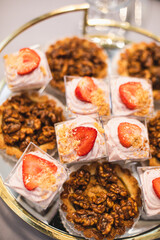 Various types of cakes with cream and strawberries, walnuts, cakes on round tray at party, holiday. 