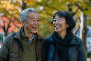 Smiling and happy senior Japanese couple enjoys a leisure walk in the city park. They radiating happiness and warmth.