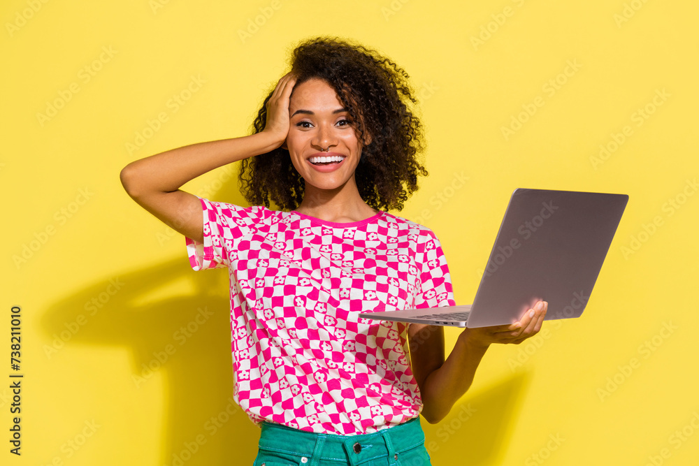 Poster Photo of cheerful lovely person arm touch head toothy smile hold netbook isolated on yellow color background