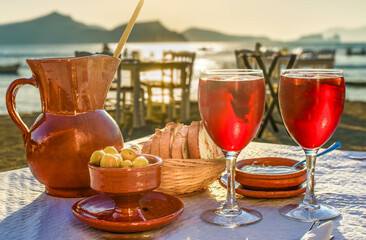 A pitcher and 2 glasses of sangria with side dishes in a Mediterranean restaurant at sunset