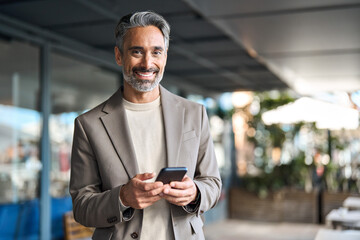 Happy mature older business man executive using mobile cell phone outdoors. Middle aged businessman...